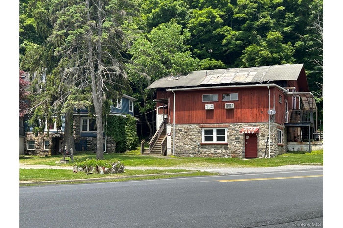 View of front facade featuring stone siding, stairs, and a wooded view