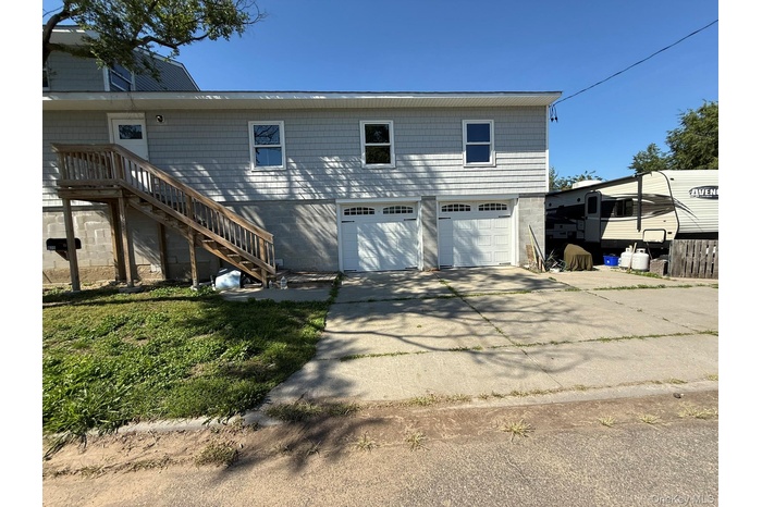 Rear view of house featuring stairs, concrete driveway, and a garage