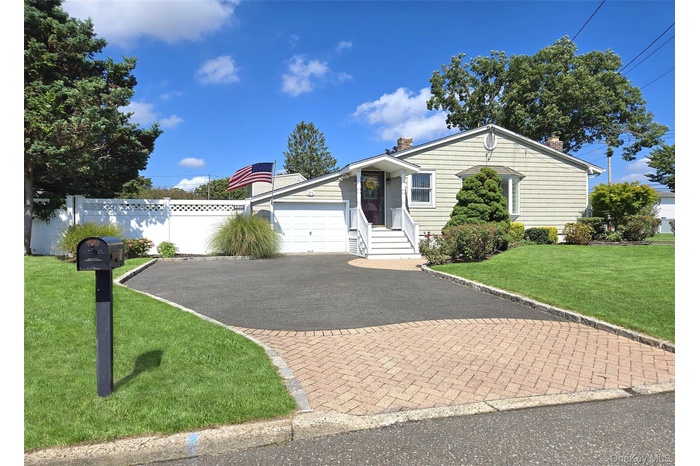 View of front facade featuring driveway, a chimney, and an attached garage