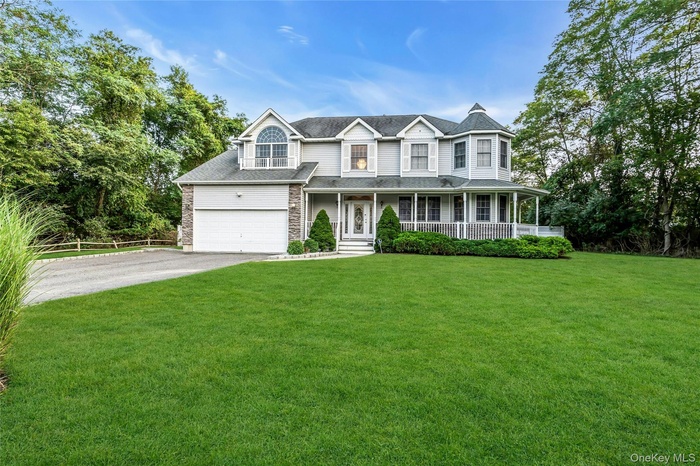 View of front of house with covered porch, driveway, and a front yard