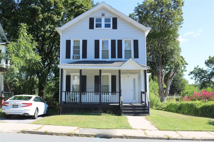 View of front of property with a porch and a front lawn
