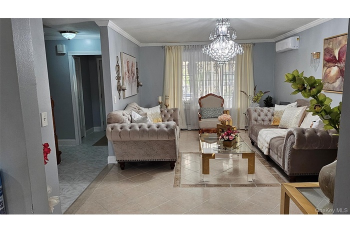 Sitting room featuring light tile patterned flooring, ornamental molding, a chandelier, and an AC wall unit