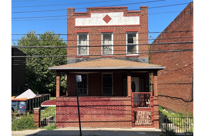 View of front facade with brick siding, a porch, and a shingled roof
