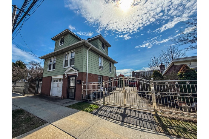 View of front of house with a gate, concrete driveway, fence, an attached garage, and brick siding
