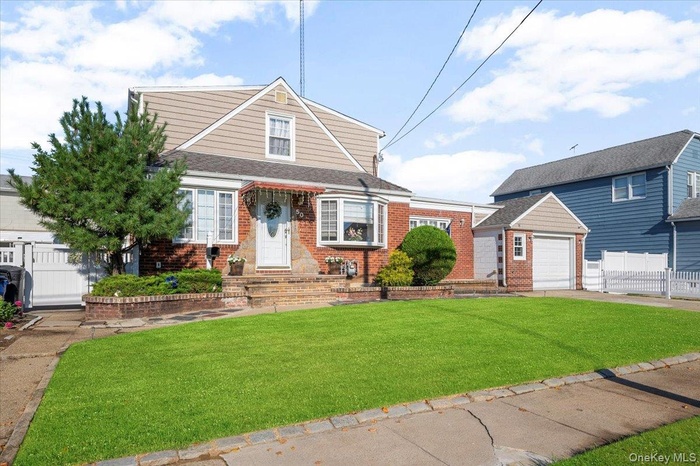 View of front of home featuring roof with shingles, driveway, a garage, an outdoor structure, and brick siding