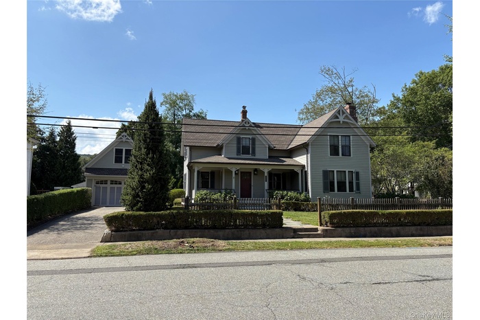 Victorian-style house with a porch, driveway, a chimney, and a garage