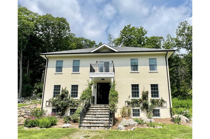 View of front of house with a balcony and stucco siding
