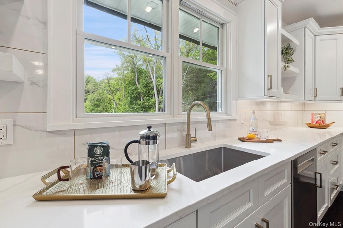 Kitchen with open shelves, white cabinetry, and decorative backsplash