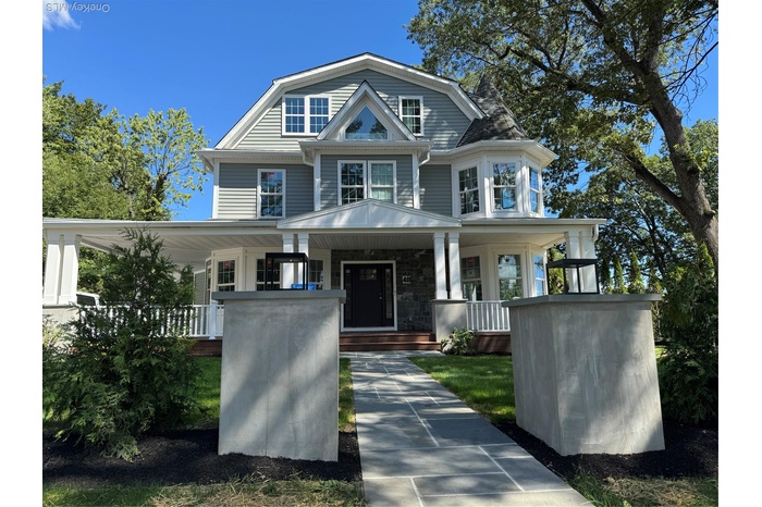 View of front of house with a porch, stone siding, and a gambrel roof