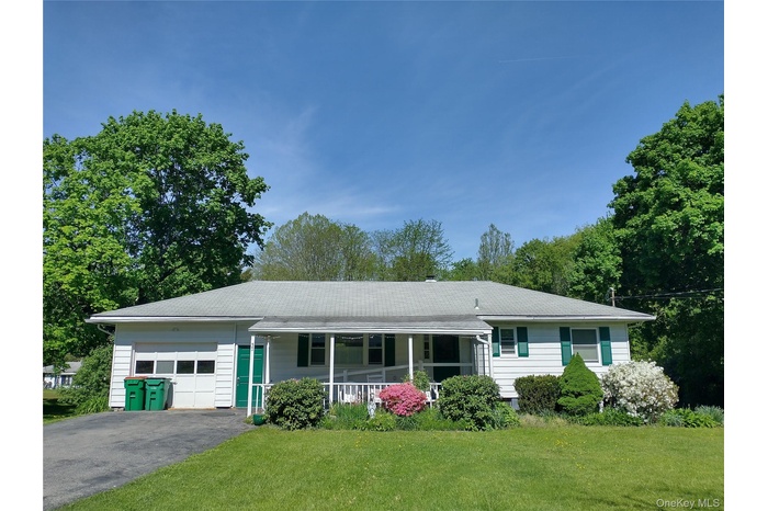 Single story home featuring a garage, covered porch, a front yard, and asphalt driveway