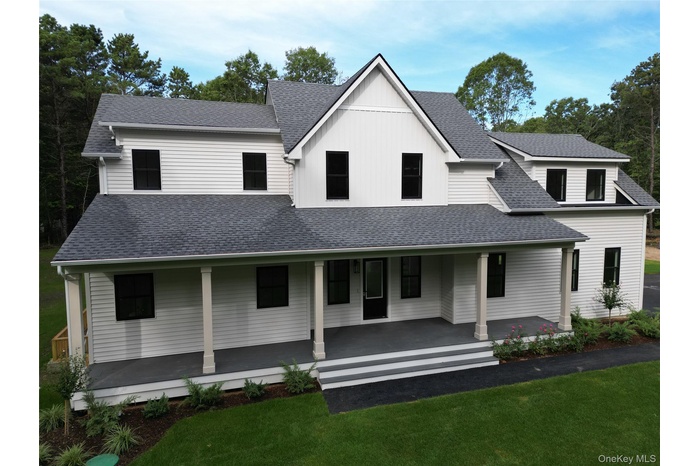 Modern farmhouse style home with covered porch, a front lawn, a shingled roof, and board and batten siding