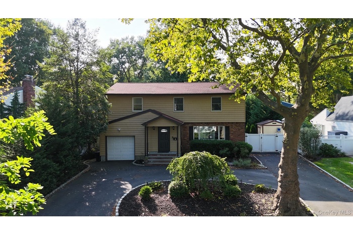 View of front of home featuring driveway, brick siding, a garage, and a gate