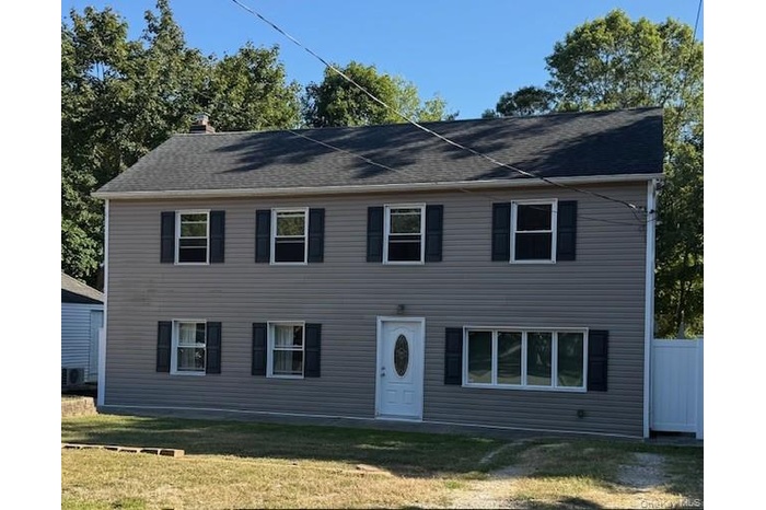Colonial inspired home featuring a front lawn and a chimney