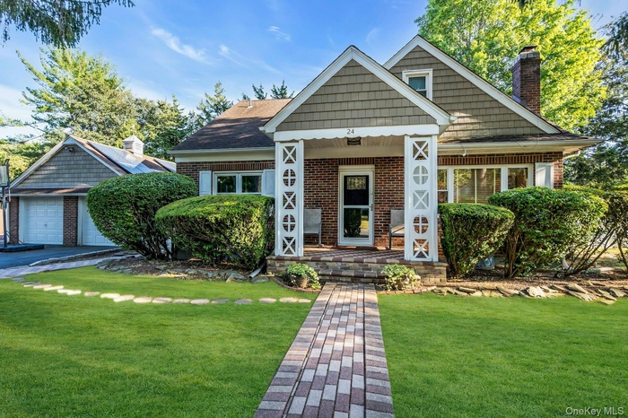 View of front of house featuring a front yard, a porch, brick siding, and a garage