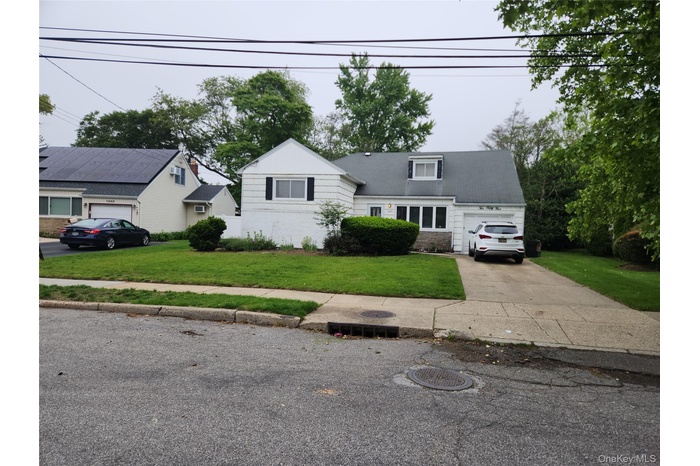 View of front of home with an attached garage, a front yard, and concrete driveway