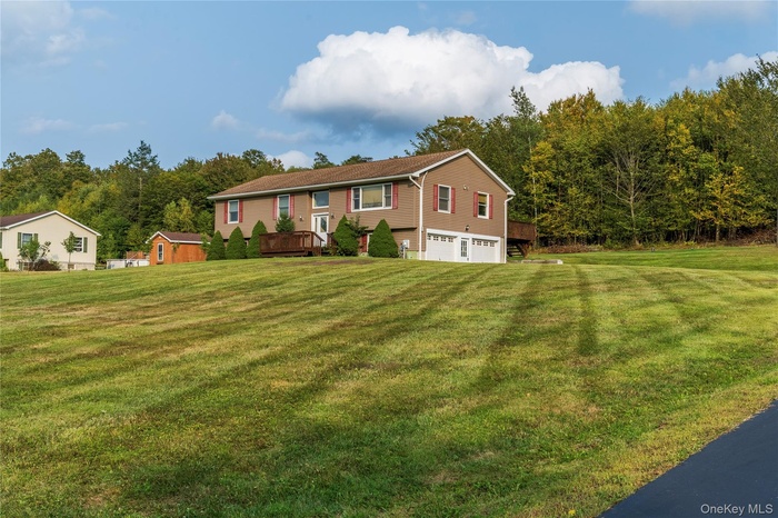 View of front of home with a front yard, a garage, and a wooden deck