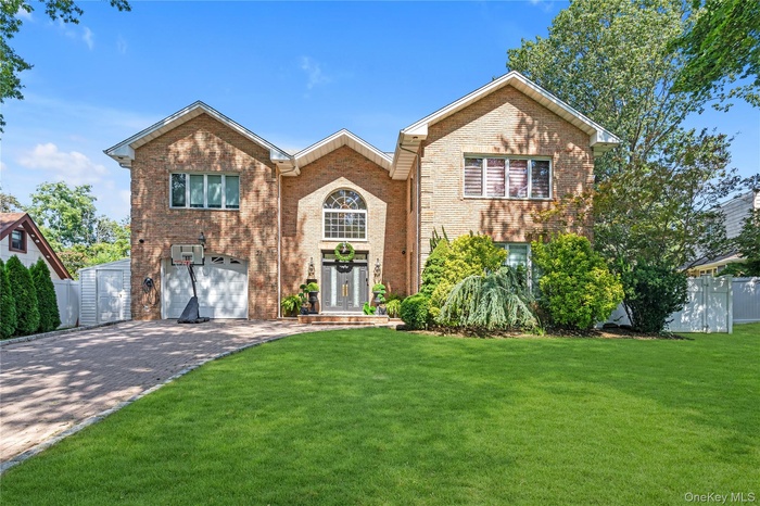 Traditional-style house featuring decorative driveway, brick siding, and an attached garage