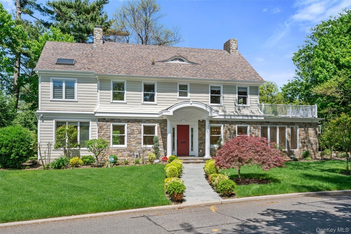 View of front of house featuring a chimney, a front lawn, and stone siding