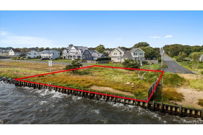 Aerial view of residential area featuring a large body of water and property parcel outlined