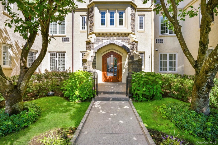 Property entrance featuring stone siding, a gate, stucco siding, and a lawn