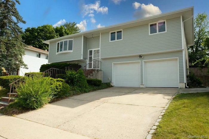 Raised ranch featuring concrete driveway and an attached garage
