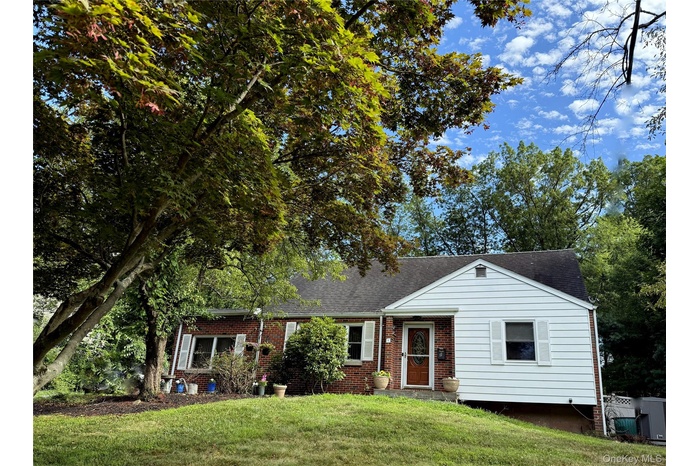 View of front of property with brick siding, roof with shingles, and a front lawn