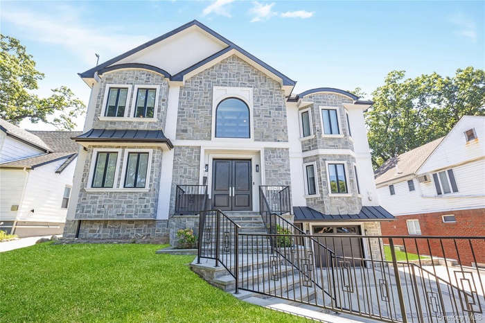 French country inspired facade with stone siding, a standing seam roof, a metal roof, and an attached garage