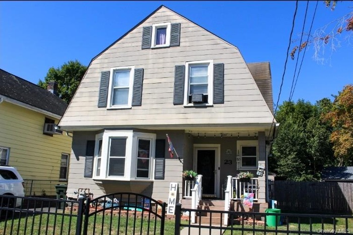 Dutch colonial featuring a gambrel roof, a porch, a fenced front yard, and a gate