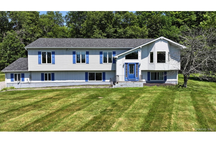 Bi-level home with roof with shingles, a front lawn, and view of scattered trees