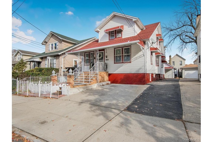Bungalow with covered porch, a fenced front yard, roof with shingles, and driveway