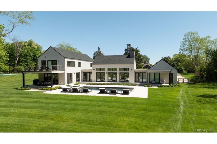 Back of house featuring a balcony, a patio area, an outdoor pool, an outdoor living space, and a lawn