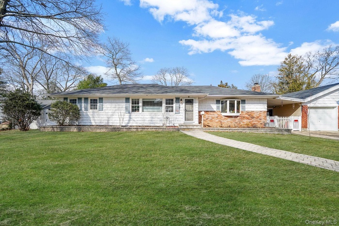 Single story home featuring a chimney, a garage, and brick siding