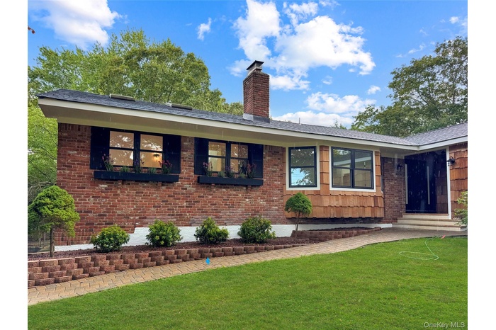 Ranch-style house with a front yard, brick siding, a chimney, and entry steps