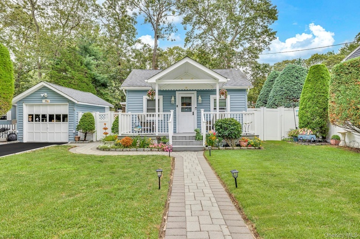 View of front of house featuring roof with shingles, a porch, an outbuilding, and a front yard