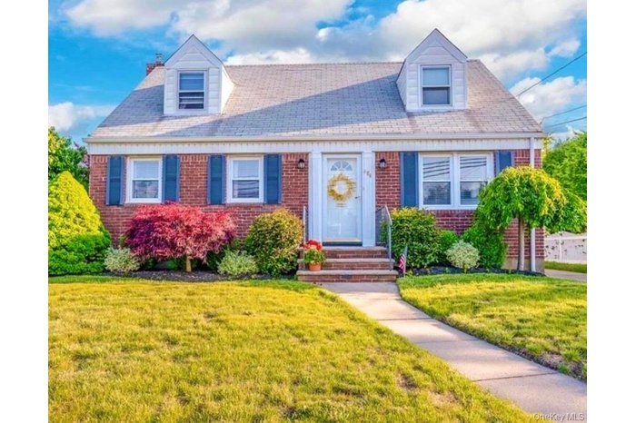 Cape cod home featuring brick siding and a front yard