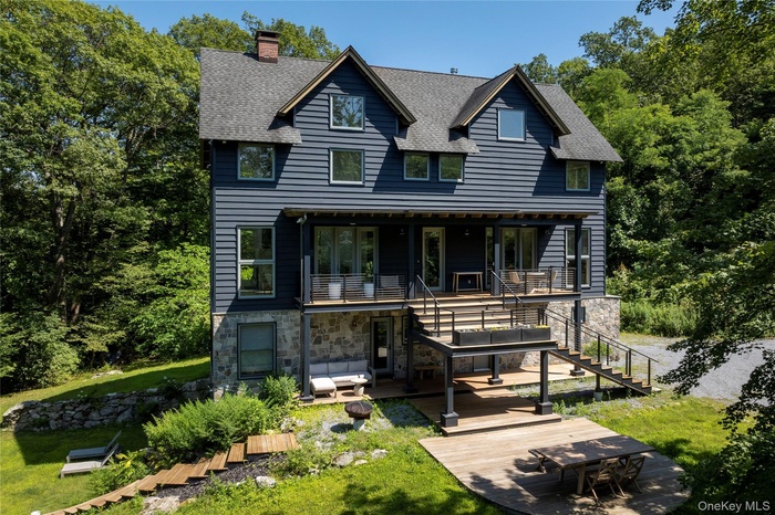 View of front of house featuring stairs, a shingled roof, a chimney, and stone siding