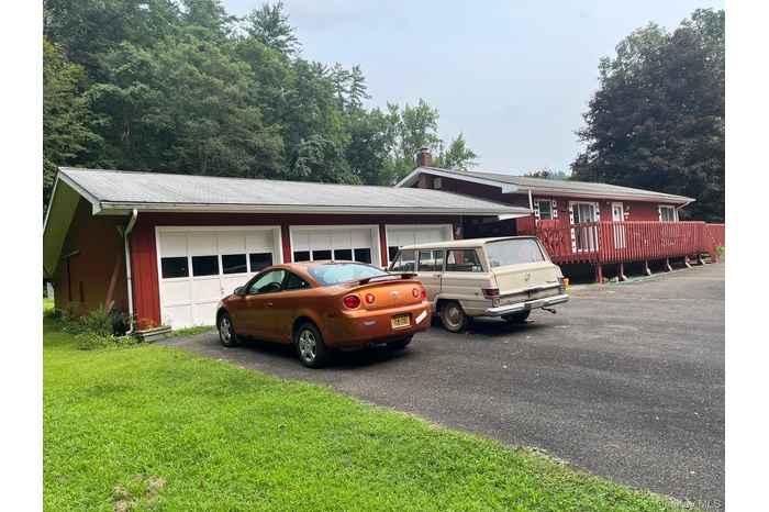 View of front facade featuring a chimney, driveway, a front yard, and a garage