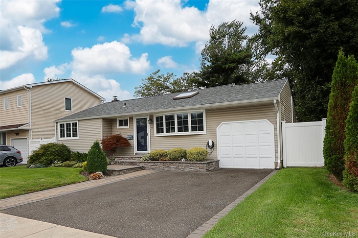Single story home featuring roof with shingles, asphalt driveway, and an attached garage