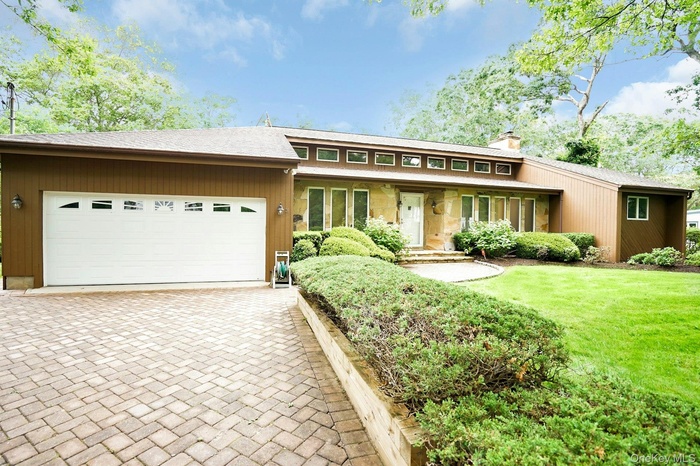 View of front of home with a chimney, decorative driveway, a garage, a front lawn, and roof with shingles