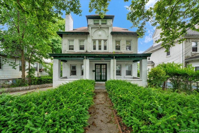 Italianate-style house featuring stucco siding, covered porch, a chimney, and french doors