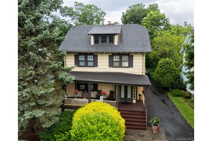 American foursquare style home featuring a shingled roof, a chimney, a porch, and asphalt driveway