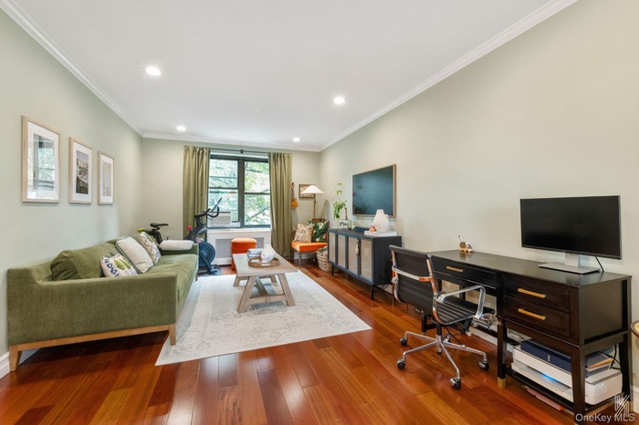Living area with ornamental molding, wood finished floors, recessed lighting, and a desk