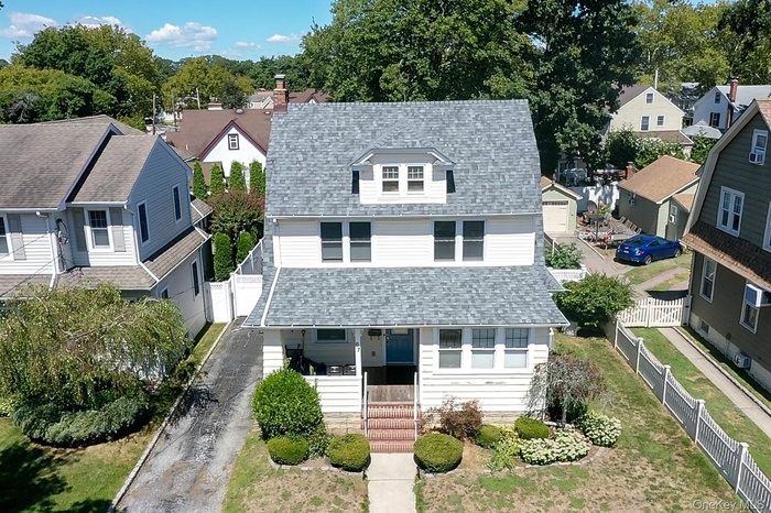 Traditional style home featuring covered porch, roof with shingles, a residential view, driveway, and a garage