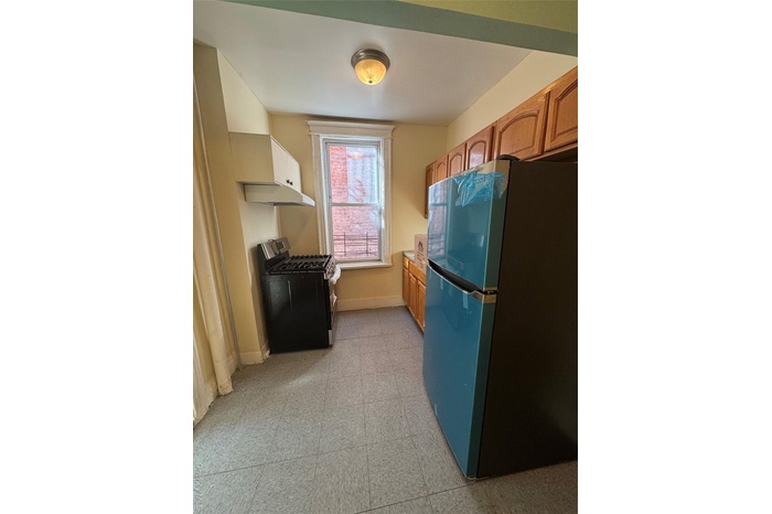 Kitchen with refrigerator, stove, extractor fan, light flooring, and light countertops