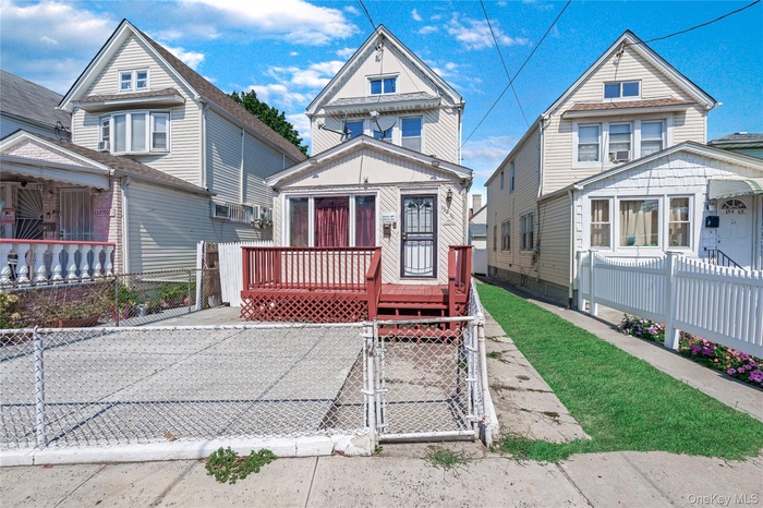 View of front of home with a gate, a wooden deck, and a fenced front yard