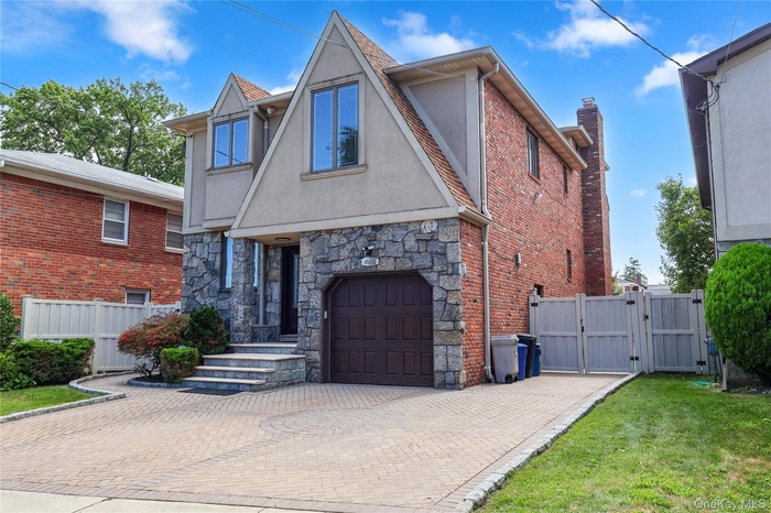 View of front of property featuring a gate, stucco siding, decorative driveway, stone siding, and an attached garage