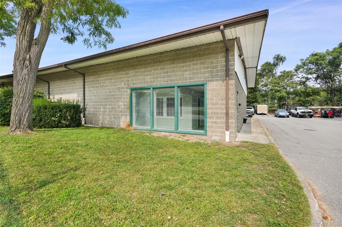 Back of house featuring concrete block siding and a lawn