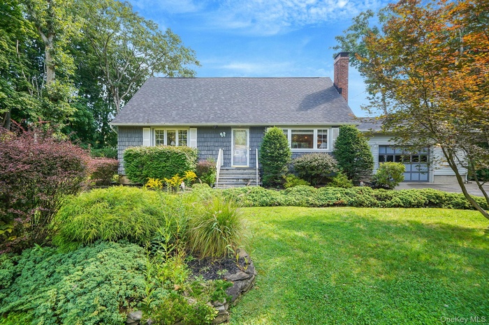 View of front facade with roof with shingles, a chimney, and a front lawn