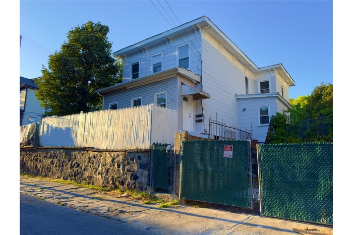 Italianate-style house with a fenced front yard and a gate