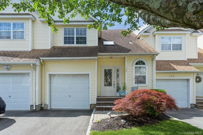 Traditional home featuring an attached garage, driveway, and a shingled roof